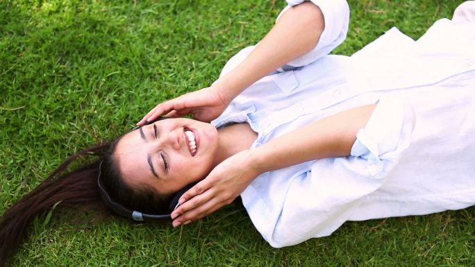 在一个阳光明媚的日子里，一个漂亮的女孩躺在草地上听音乐