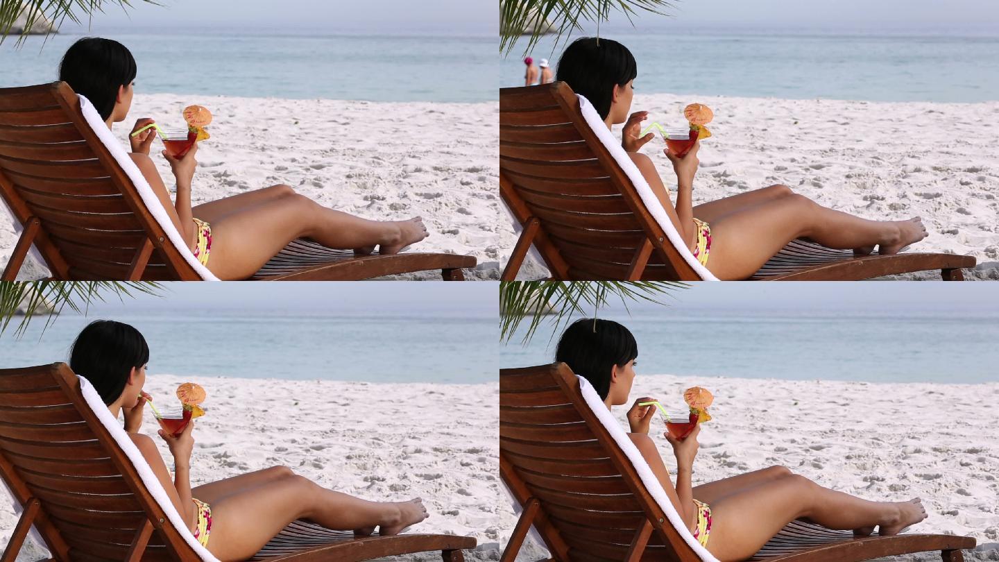 女人在沙滩上的椅子上喝鸡尾酒特写