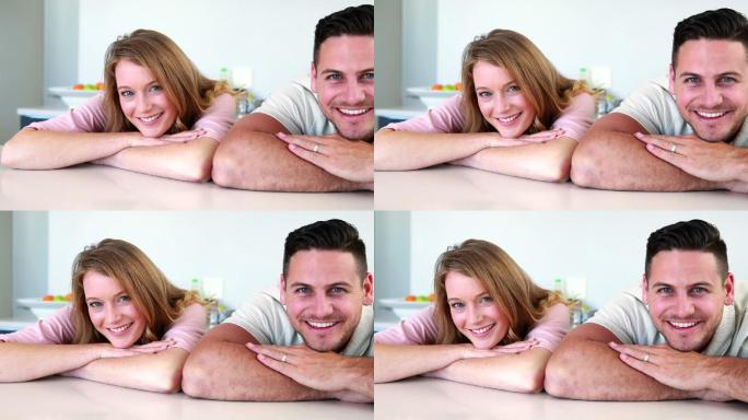 一对幸福的夫妇在厨房里靠在柜台上对着镜头微笑