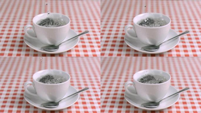 用超慢的动作把水倒进厨房桌子上的茶杯里