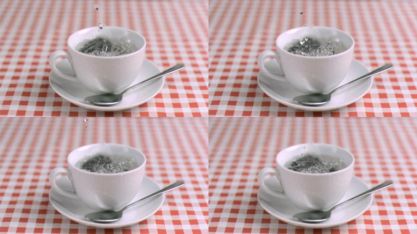 用超慢的动作把水倒进厨房桌子上的茶杯里