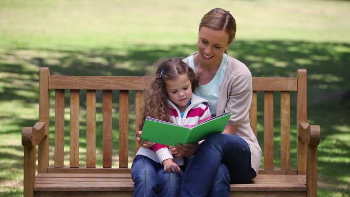 妈妈和女儿一起坐在公园看书特写