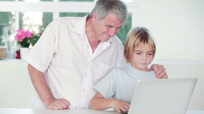 一个孩子和他爷爷在厨房用笔记本电脑