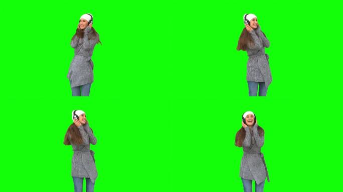 绿色屏幕下女人穿着冬装听音乐特写