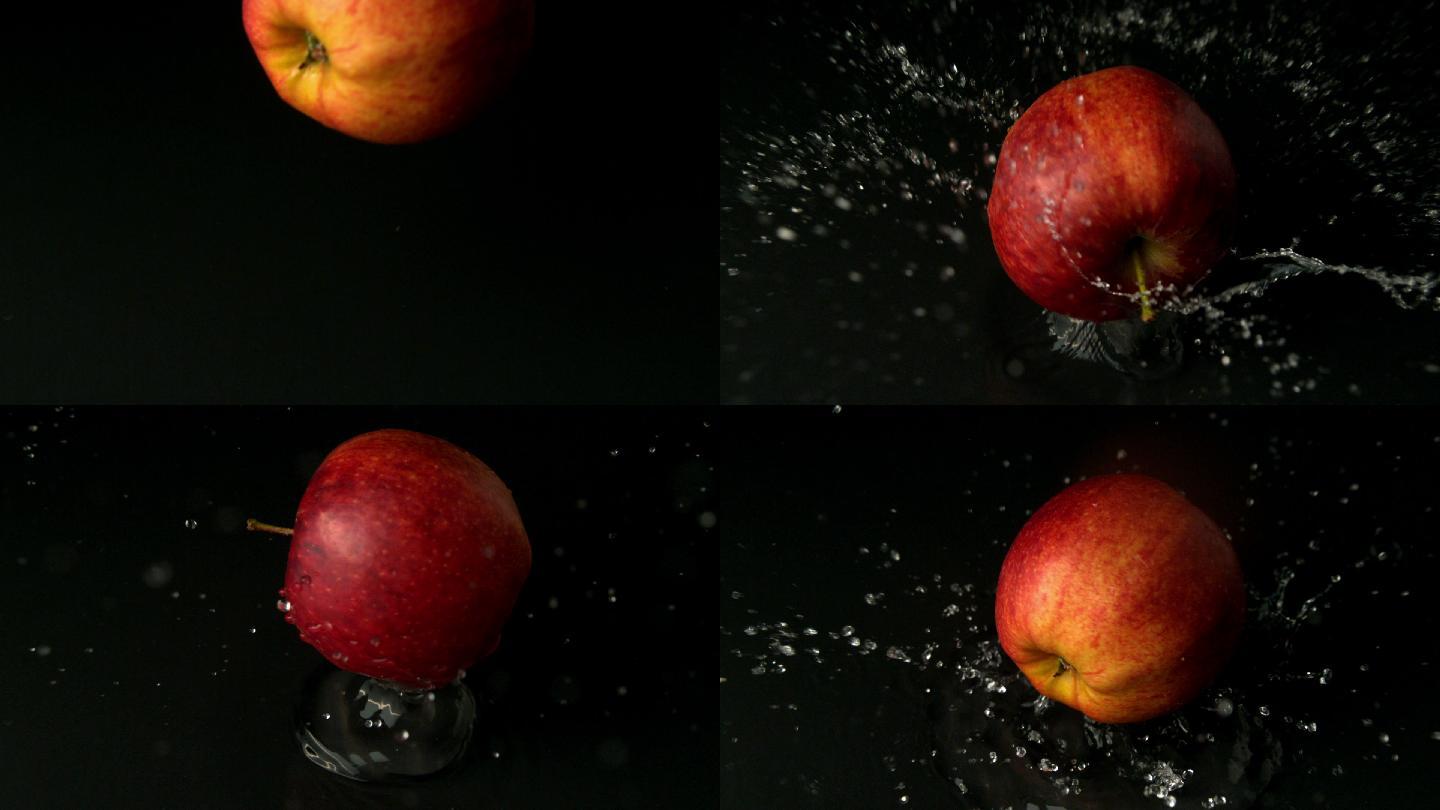 红苹果落在潮湿的黑色表面的慢动作