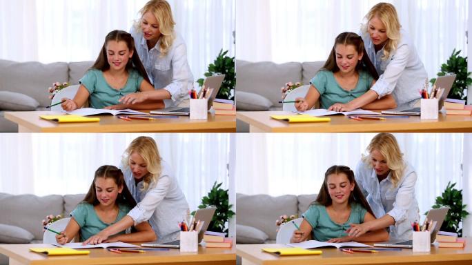 母亲帮助她的女儿做作业，微笑着在客厅的书桌上
