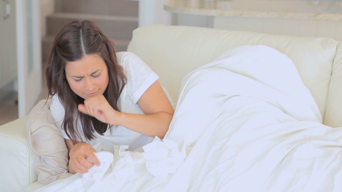 生病的女人打喷嚏和坐在沙发上看电视的视频