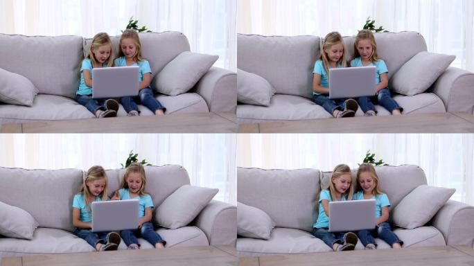 两姐妹在沙发上玩笔记本电脑