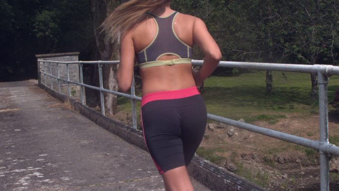 女人穿着运动服在户外桥上跑步特写