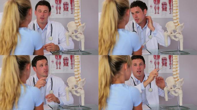 脊椎治疗师与他的病人交谈，并使用脊柱模型解释一些事情