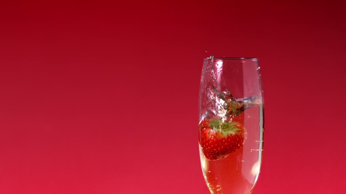 一颗草莓掉进香槟杯特写