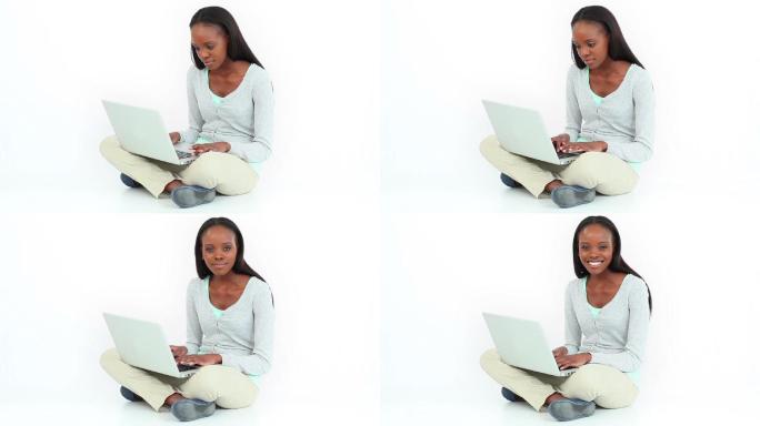 女子盘腿在白色背景下使用笔记本电脑