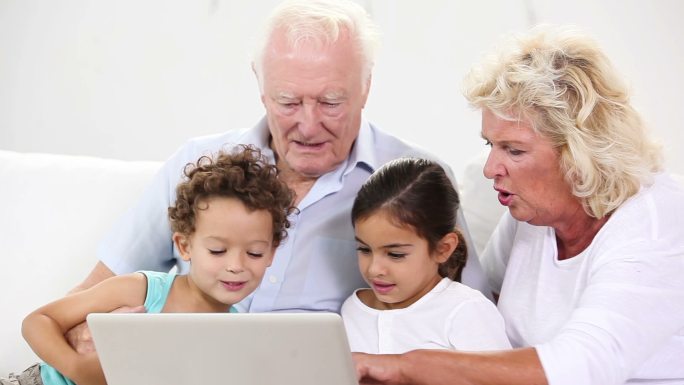 孩子和祖父母在家里使用笔记本电脑