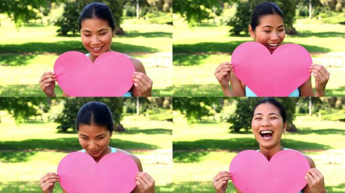 健康的亚洲女孩展示了一个纸心脏在一个阳光明媚的日子