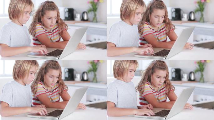 两个孩子在厨房使用笔记本电脑