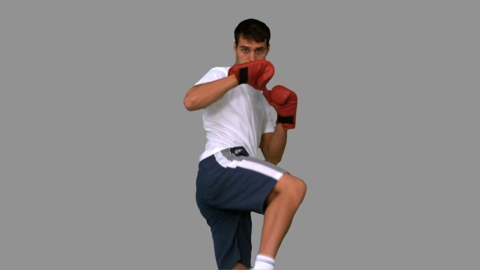 男人在灰色背景下戴着拳击手套打拳特写
