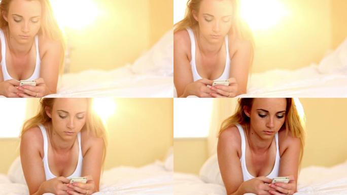美丽的少女在她家里卧室的床上发短信