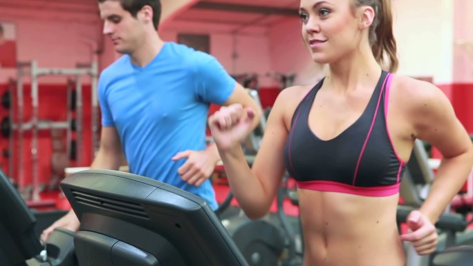 女人和男人在健身房的跑步机上跑步