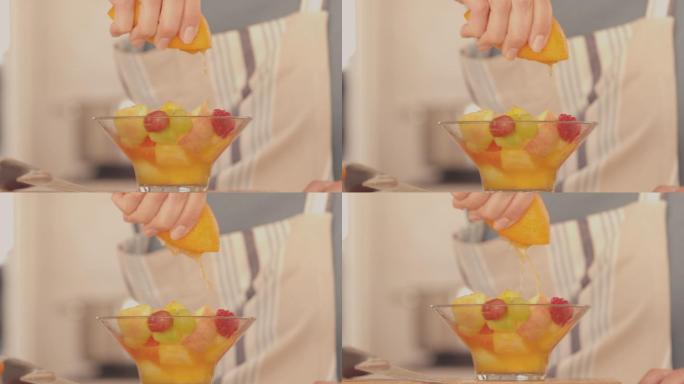 在慢镜头中，女人在水果沙拉上挤橘子