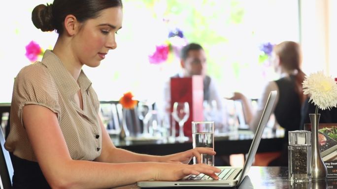 一个严肃漂亮的女商人在高档餐厅里用笔记本电脑工作
