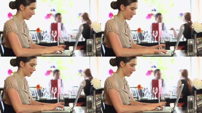 一个严肃漂亮的女商人在高档餐厅里用笔记本电脑工作