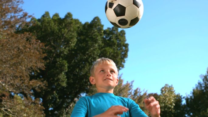一个小男孩在用慢镜头顶着一个足球