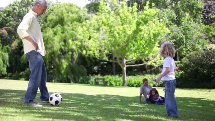 爸爸和他的孩子们在公园里踢足球特写