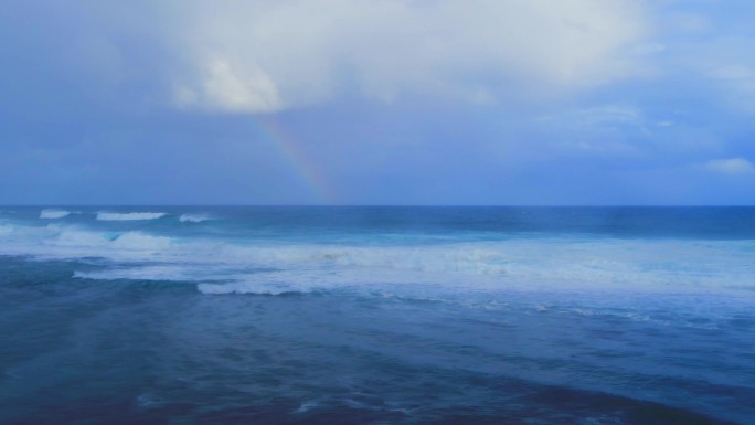 航拍彩虹下波涛汹涌的海面素材