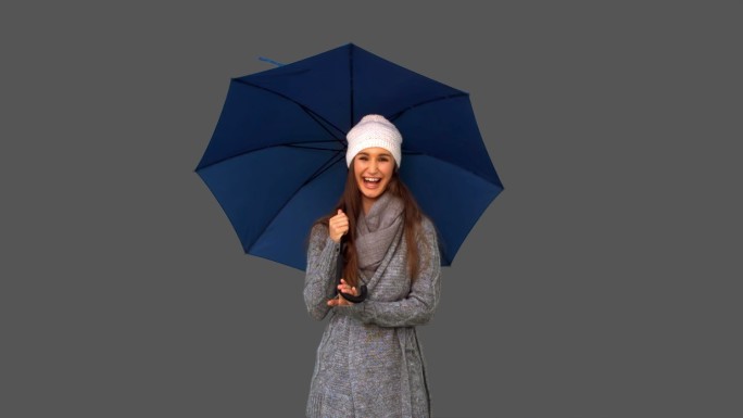 女孩穿着冬装拿着伞在灰色背景微笑特写