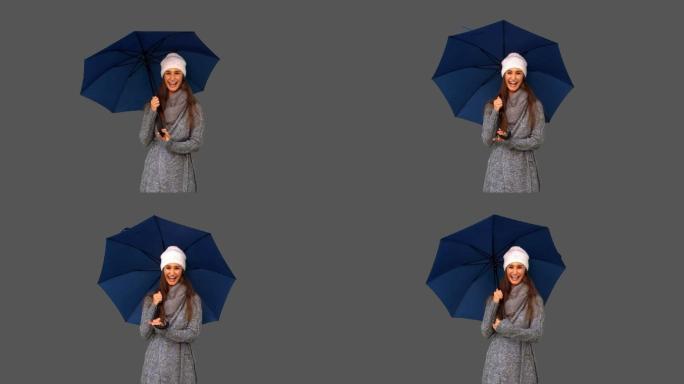 女孩穿着冬装拿着伞在灰色背景微笑特写
