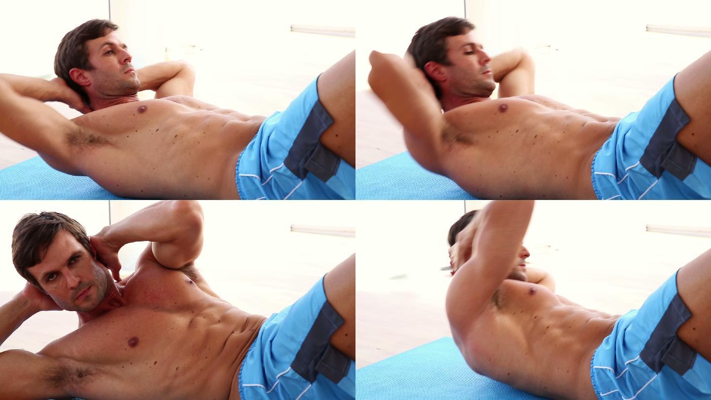 健身男赤裸上身在健身房做仰卧起坐