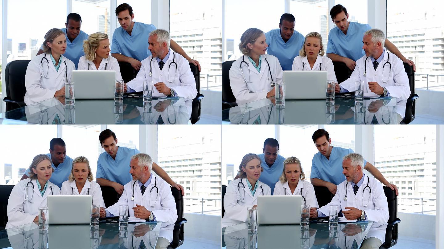 一群医生在会议室里一起使用笔记本电脑