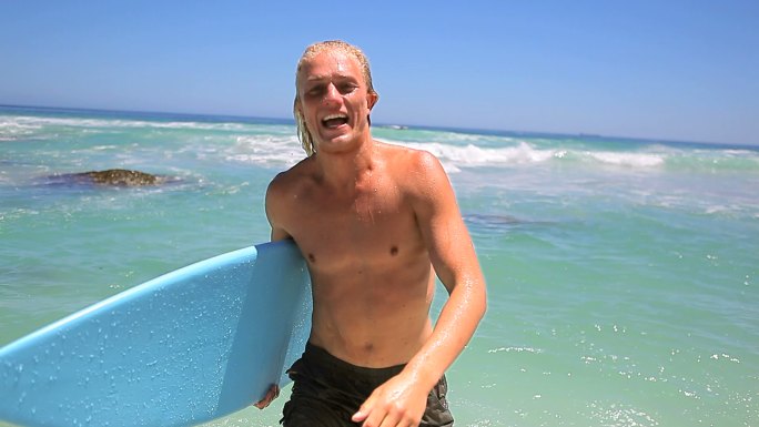 男人拿着冲浪板看镜头微笑特写