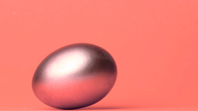 银色鸡蛋在粉色背景下翻滚特写