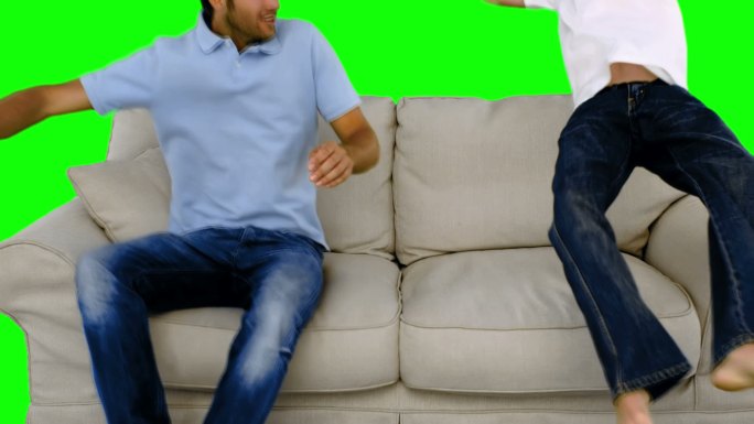 绿色屏幕下爸爸和儿子跳到沙发上特写