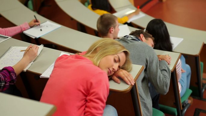 在大学的讲堂里，学生在课桌上睡觉