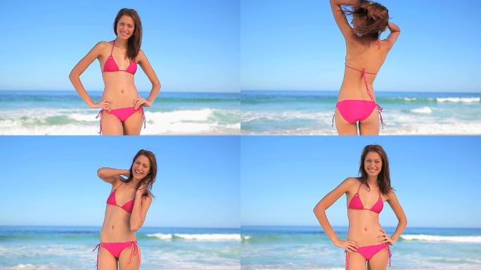 女人穿着比基尼站在沙滩边注视镜头特写