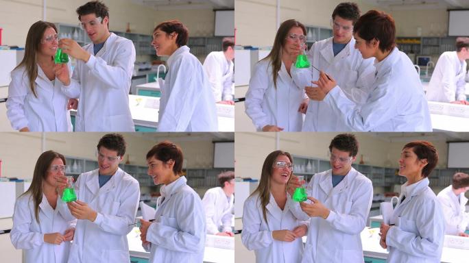 科学家们在实验室里分组研究绿色液体的烧杯，他们的老师过来给他们讲解