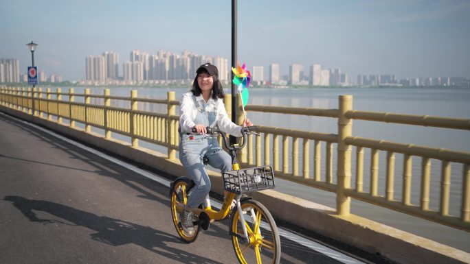 女生在湖边小路上骑共享单车