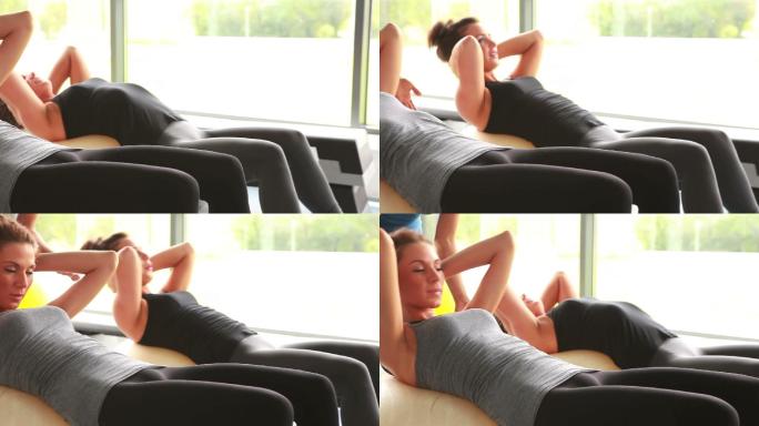 两个女人在健身房做仰卧起坐