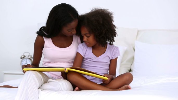 妈妈和她的女儿在家里的床上看书