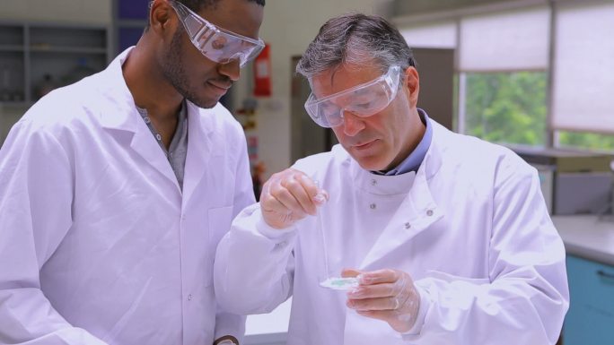 化学家们在实验室里观察烧杯里的液体特写