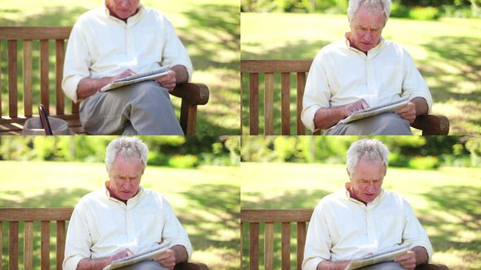 一个退休男子在公园里看报纸特写