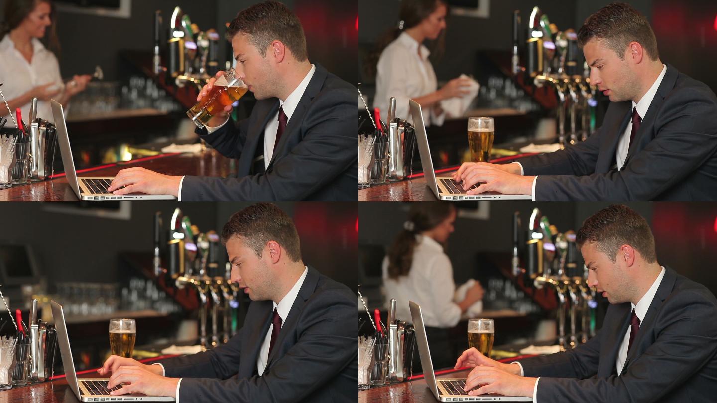 男人一边喝啤酒一边用电脑工作特写