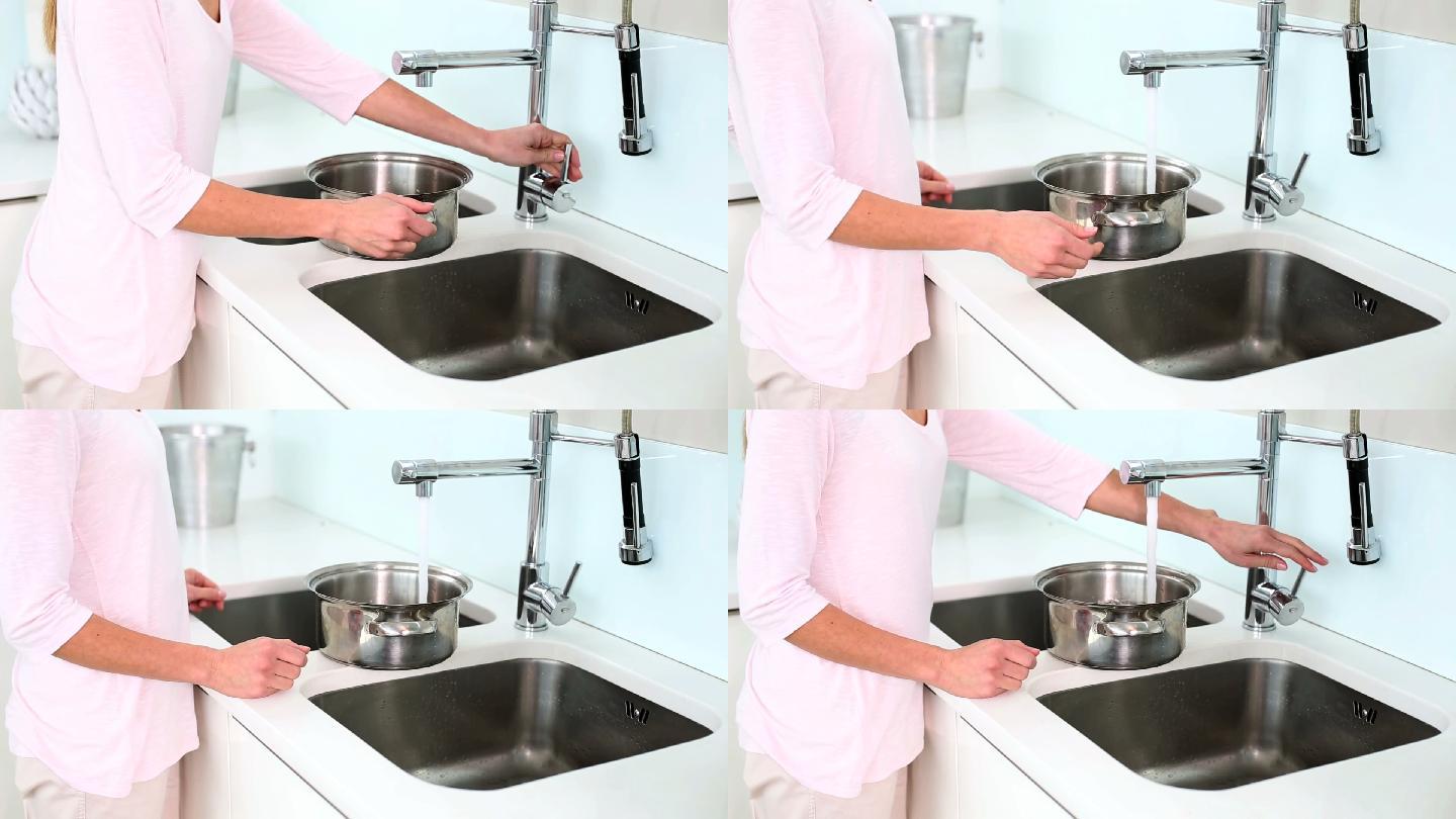 女人在厨房往平底锅里注水特写