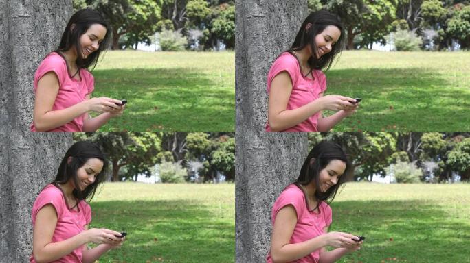 一个微笑的女人在公园里用手机的视频