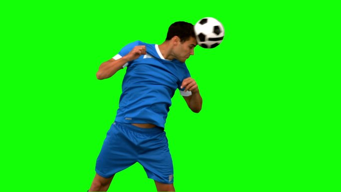 一个足球运动员在绿色背景下练习足球特写