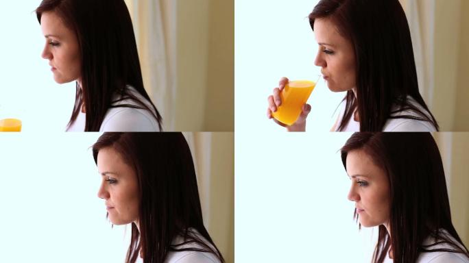 年轻女子喝着橙汁，看着镜头