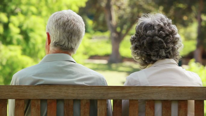 一对老夫妇坐在长椅上聊天特写