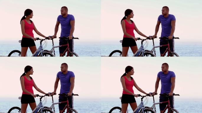 一对情侣推着自行车在海边聊天特写